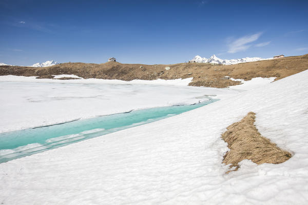 Turquoise water of Lake Emet surrounded by snow during the spring thaw Spluga Valley Sondrio Valtellina Lombardy Italy Europe