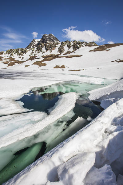 Spadolazzo Peak is reflected in the calm waters of Lake Emet in thaw. Madesimo. CHiavenna Valley. Spluga Valley. Valtellina. Lombardy. Italy. Europe