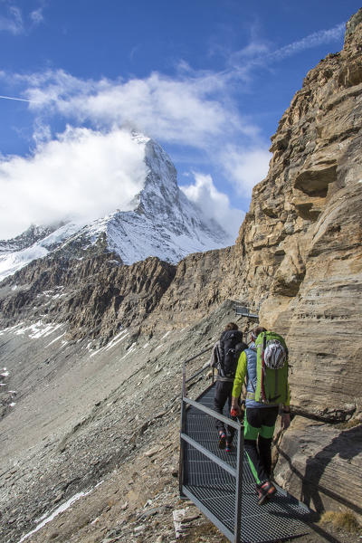 Hikers run through walkways that allow to reach the summit of the Matterhorn. Zermatt. Switzerland. Europe