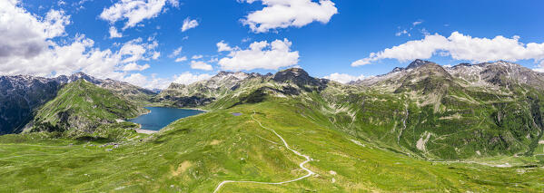 Aerial panoramic of green meadows of Andossi with lake Montespluga on background, Madesimo, Valle Spluga, Valtellina, Lombardy, Italy