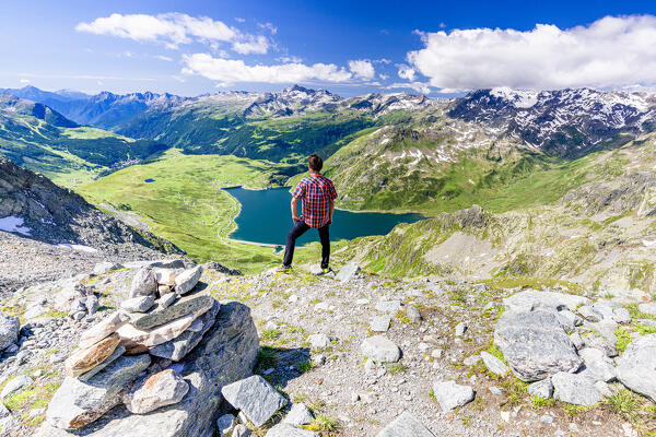 Hiker looking at lake Montespluga standing on mountain peak, Madesimo, Valle Spluga, Valtellina, Lombardy, Italy (MR)