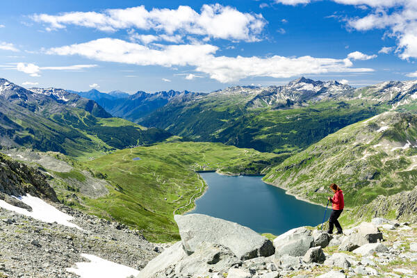 Cheerful woman enjoying a summer hike nearby an alpine lake, Madesimo, Valle Spluga, Valtellina, Lombardy, Italy