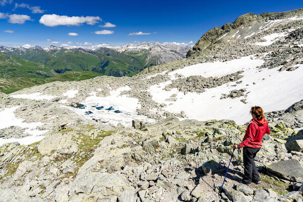 Hiker woman looking at Laghi Azzurri from path, Madesimo, Valle Spluga, Valtellina, Lombardy, Italy