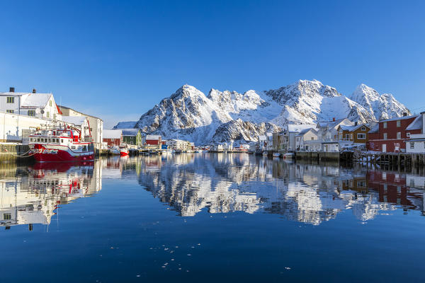 Houses and mountains reflected in the waters of Henningsvaer fjord. Lofoten Islands. Norway. Europe