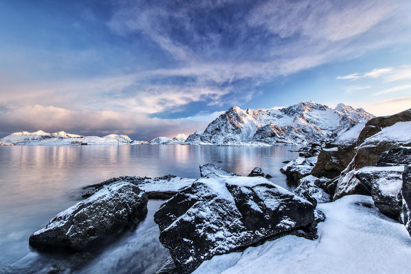 The colors of dawn light up the sea in Henningsvaer fjord. Lofoten Islands. Norway. Europe