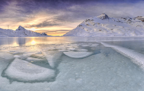 Sunrise lights the  frozens surface ok White Lake at Bernina Pass. Canton of Graubuenden. Engadine. Switzerland. Europe