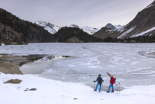 Hikers admire Bregaglia Valley from Lake Cavloc at sunrise. Switzerland Europe