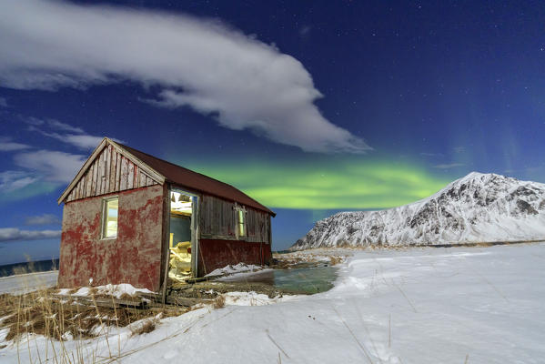 Northern Lights over an abandoned log cabin surrounded by snow and ice. Flakstad. Lofoten Islands Northern Norway Europe