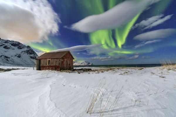 Northern Lights over an abandoned log cabin surrounded by snow and ice. Flakstad. Lofoten Islands Northern Norway Europe