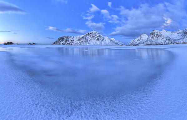 Blue of dusk dominates the scenery in Flakstad with its cold sea and the snowy peaks. Lofoten Islands Northern Norway Europe