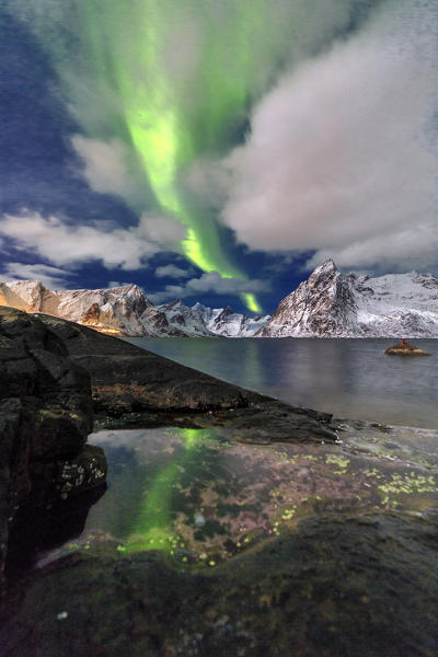 Northern Lights illuminate Hamnøy village and the snowy peaks. Lofoten Islands Northern Norway Europe