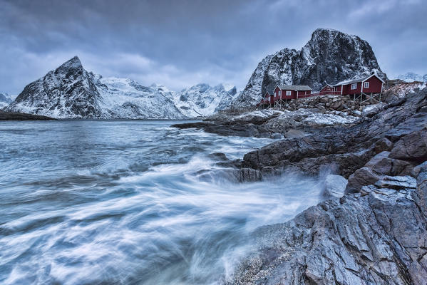 Dusk lights on the typical red houses and the rough sea. Hamnøy. Lofoten Islands Norway Europe