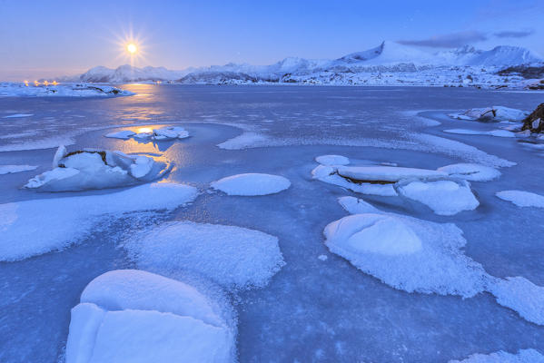 Reflections of full moon in the frozen sea. Lyngedal.  Lofoten Islands Norway Europe