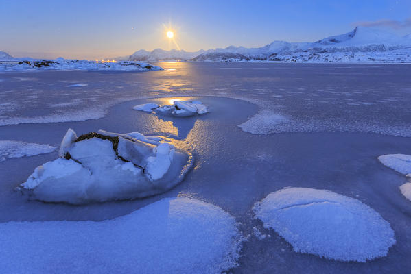 Reflections of full moon in the frozen sea. Lyngedal.  Lofoten Islands Norway Europe