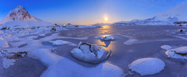 Reflections of full moon in the frozen sea. Lyngedal.  Lofoten Islands Northern Norway Europe