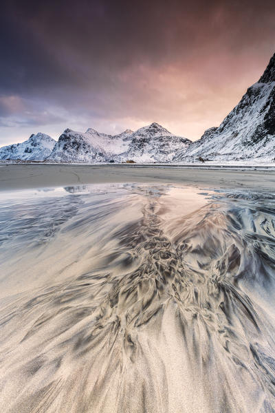 Pink sky on the  surreal Skagsanden beach surrounded by snow covered mountains. Lofoten Islands Northern Norway Europe