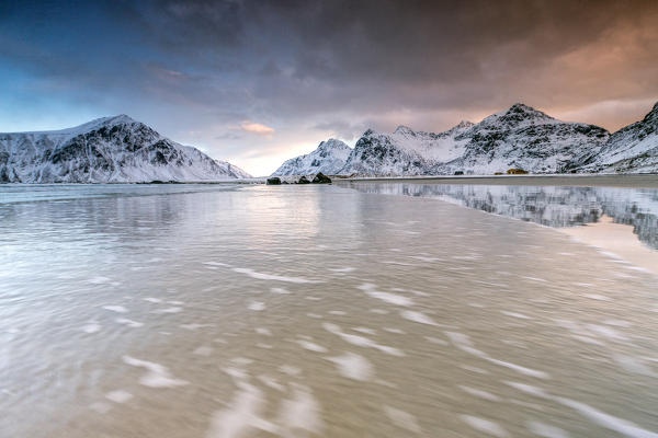 Pink sky on the  surreal Skagsanden beach surrounded by snow covered mountains.  Lofoten Islands Northern Norway Europe