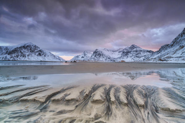 Waves on the  surreal Skagsanden beach surrounded by snow covered mountains. Lofoten Islands Norway. Europe