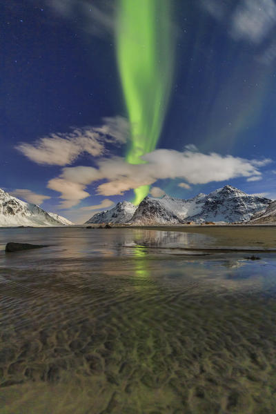 Northern Lights illuminate Skagsanden beach and the snowy peaks. Lofoten Islands Northern Norway Europe