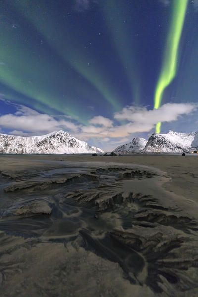 Northern Lights illuminate Skagsanden beach and the snowy peaks. Lofoten Islands Northern Norway Europe