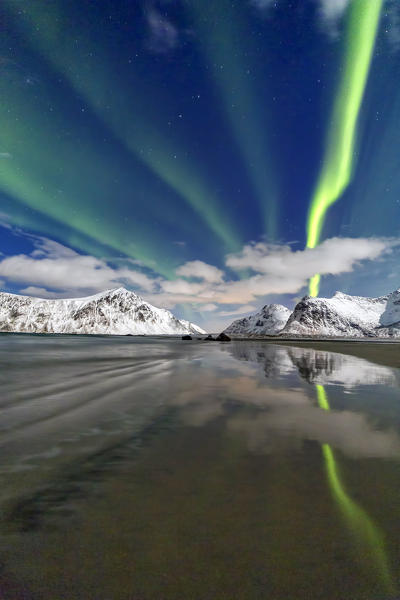 Northern Lights illuminate Skagsanden beach and the snowy peaks. Lofoten Islands Northern Norway Europe