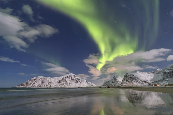 Northern Lights illuminate Skagsanden beach and the snowy peaks. Lofoten Islands Northern Norway Europe