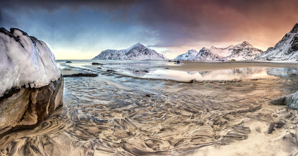 Pink sky on the  surreal Skagsanden beach surrounded by snow covered mountains. Lofoten Islands Northern Norway Europe