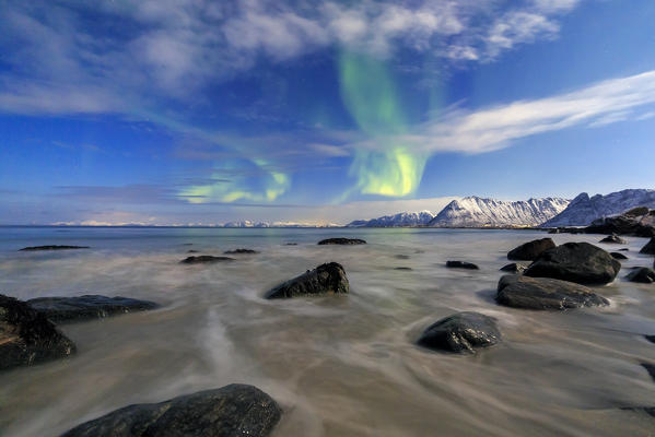 Northern Lights illuminate the landscape around Gymsøyand and the snowy peaks. Lofoten Islands Northern Norway Europe