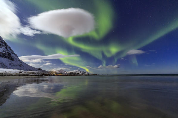 Northern Lights illuminate the landscape around Skagsanden and the snowy peaks. Lofoten Islands Northern Norway Europe