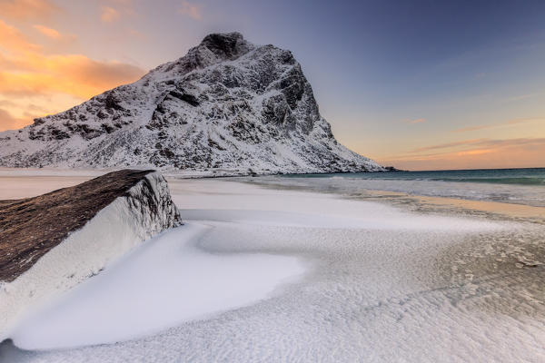 Dawn illuminates the rocks shaped by wind surrounded by fresh snow. Uttakleiv Lofoten Islands Norway Europe