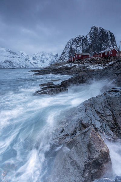 Waves crashing on the cliffs near the houses of the fishermen. Hamnøy. Lofoten Islands Northern Norway Europe