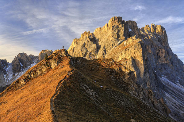 Hiker admires the peaks of Forcella De Furcia at sunrise. Funes Valley South Tyrol Dolomites Italy Europe