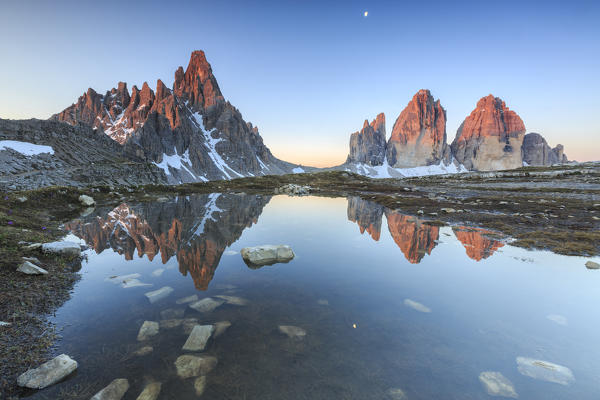 Dawn illuminates the Three Peaks and Mount Paterno reflected in the lake. Sesto Dolomites Trentino Alto Adige Italy Europe