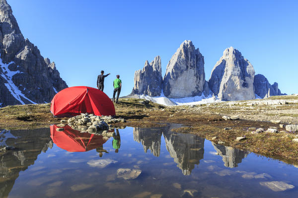 Hikers camped for the night admire the Three Peaks of Lavaredo on awakening. Sesto Dolomites Trentino Alto Adige Italy Europe