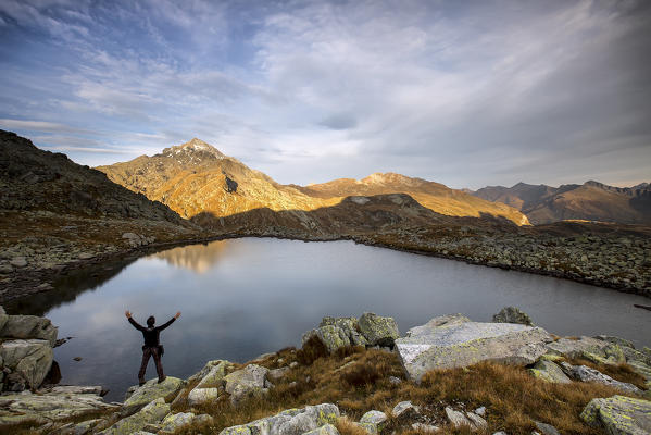 Hiker admires Lake Bergsee at sunrise Chiavenna Valley Spluga Valley Switzerland Europe