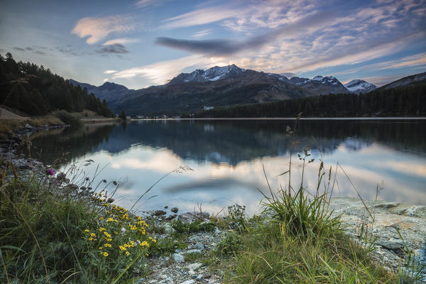 Pink sky at dawn illuminates the peaks reflected in Lake Sils Engadine Canton of Graubünden Switzerland Europe