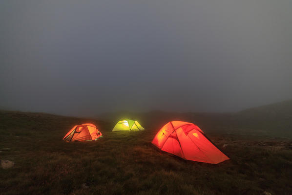 The soft lights of the tents light up the foggy dusk Minor Valley High Valtellina Livigno Lombardy Italy Europe