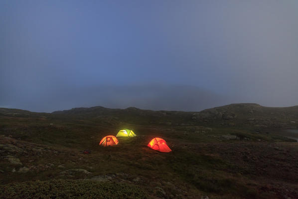 The soft lights of the tents light up the foggy dusk Minor Valley High Valtellina Livigno Lombardy Italy Europe