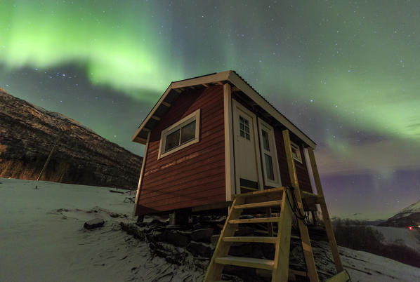 The Northern Lights illuminates the wooden cabin Oteren Storfjorden Lyngen Alps Tromsø Lapland Norway Europe