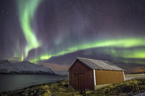 Northern Lights illuminates the wooden cabin at Svensby Lyngen Alps Tromsø Lapland Norway Europe