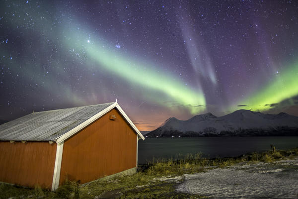 Northern Lights illuminates the wooden cabin at Svensby Lyngen Alps Tromsø Lapland Norway Europe