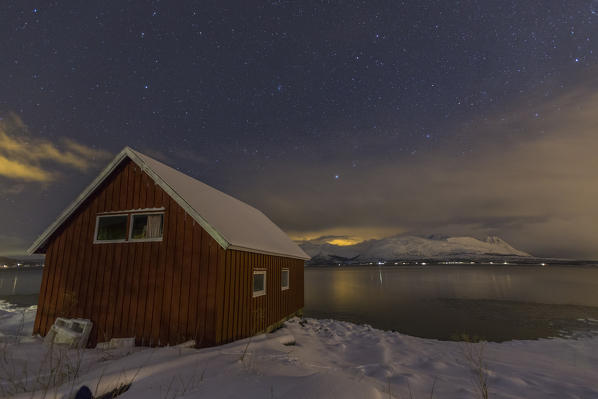 Lights illuminates the wooden cabin Lyngen Alps Tromsø Fjord Lapland Norway Europe