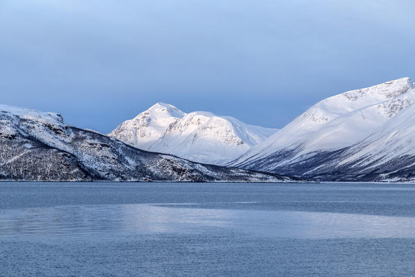 Blue sky and snowy peaks surround the cold sea Lyngen Alps Tromsø Lapland Norway Europe