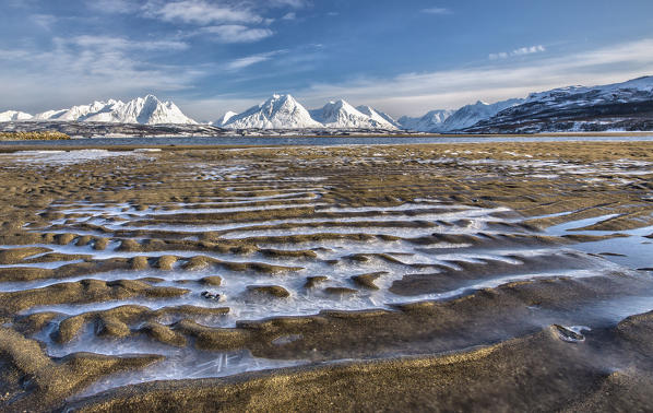 The icy sandy beach surrounding the snow capped mountains Breivikeidet Lyngen Alps Tromsø Lapland Norway Europe