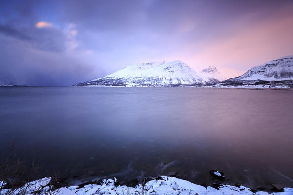 The sky turns pink at sunset and is reflected in the frozen sea Storfjorden Lapland Lyngen Alps Tromsø Norway Europe