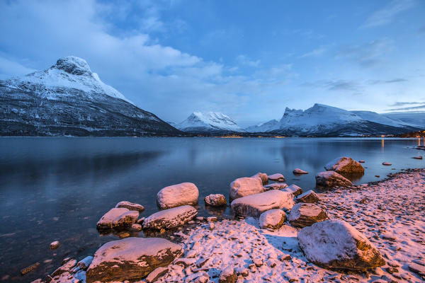 Blue sky at dusk and snowy peaks are reflected in the frozen sea Storfjorden Lapland Lyngen Alps Tromsø Norway Europe