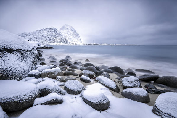 Snow covered rocks on the beach modeled by the wind surround the icy sea Pollen Vareid Flakstad Lofoten Islands Norway Europe