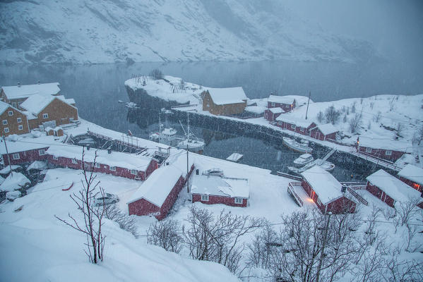 Heavy snowfall on the fishing village and the icy sea Nusfjord Lofoten Islands Norway Europe