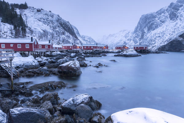 Typical fishermen houses called rorbu in the  snowy landscape at dusk Nusfjord Nordland County Lofoten Islands Norway Europe