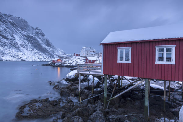 Typical fishermen houses called rorbu in the  snowy landscape at dusk Nusfjord Nordland County Lofoten Islands Norway Europe